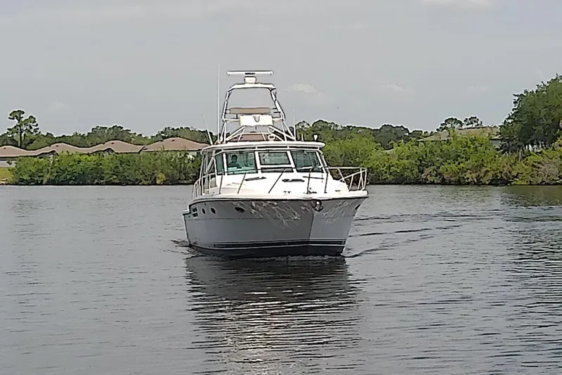 Slide: The Image of 2000 Tiara Yachts 4100 Open cruising on a calm river with lush greenery. - 8