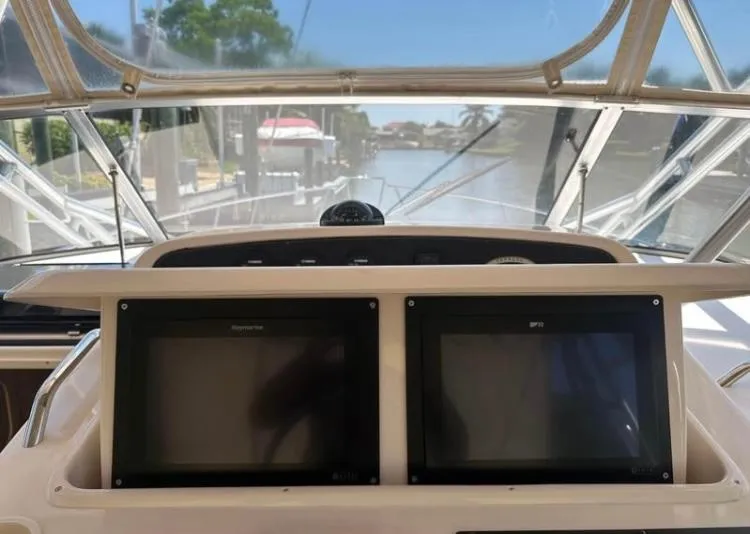 Slide: The Image of 2007 Grady-White Express 330 dashboard with dual navigation screens, docked by a scenic canal. - 4