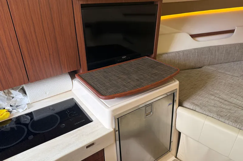 Slide: The Image of Interior of 2021 Grady-White Express 330 with TV, kitchenette, and seating area. - 10