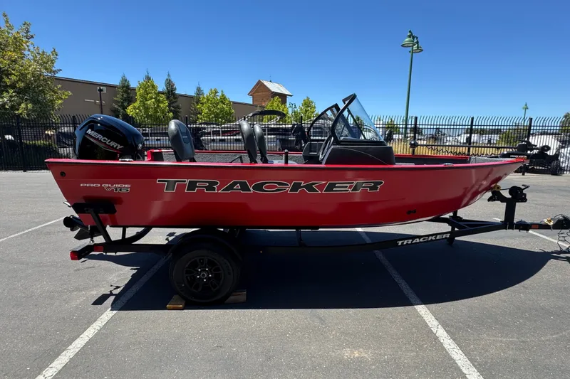 Slide: The Image of Red 2026 Tracker Pro Guide V-16 WT boat on trailer in parking lot. - 4