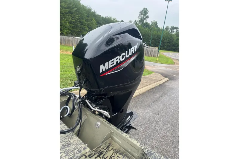Slide: The Image of 2026 Tracker Grizzly 1754 SC with Mercury outboard motor in a scenic outdoor setting. - 2
