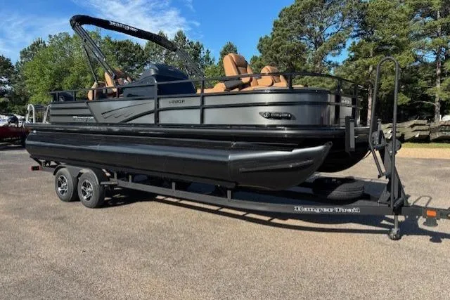 Slide: The Image of 2026 Ranger 220F pontoon boat on trailer, parked outdoors with trees in background. - 2