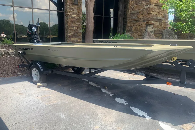 The Image of 2026 Tracker Grizzly 1654 T Sportsman boat on trailer, parked outdoors. - 0