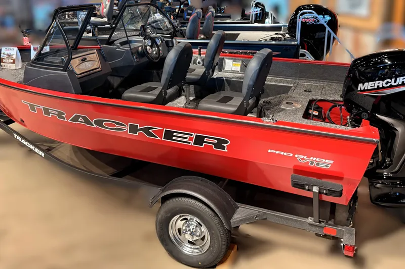 Slide: The Image of 2026 Tracker Pro Guide V-16 WT boat, red exterior, displayed indoors with Mercury engine. - 63