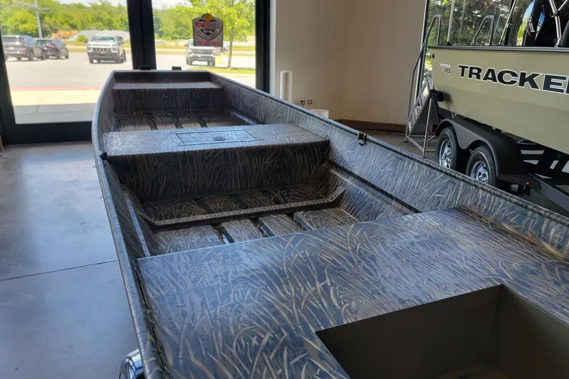 Slide: The Image of 2026 Tracker Grizzly 15 Jon boat with camouflage interior, displayed indoors. - 3