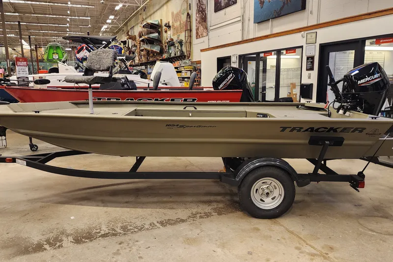 The Image of 2026 Tracker Grizzly 1654 T Sportsman boat displayed indoors on a trailer. - 0