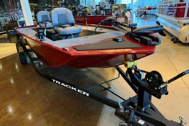 Slide: The Image of 2026 Tracker Panfish 17 boat in showroom, featuring red hull and dual seating. - 2