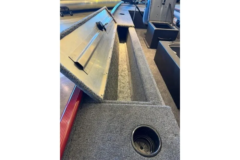 Slide: The Image of 2026 Tracker Panfish 17 boat interior storage compartment with open lid and cup holder. - 7