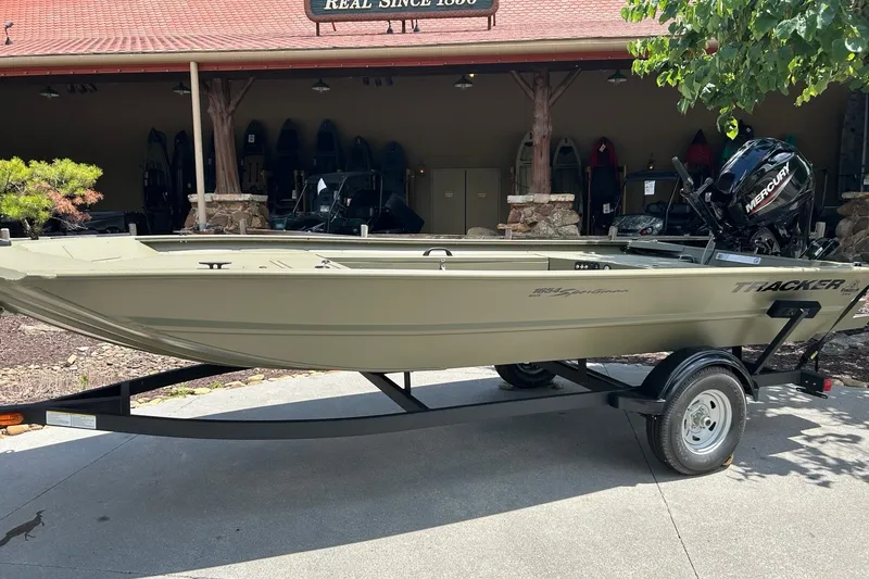 The Image of 2026 Tracker Grizzly 1654 T Sportsman boat on trailer, parked outdoors. - 0