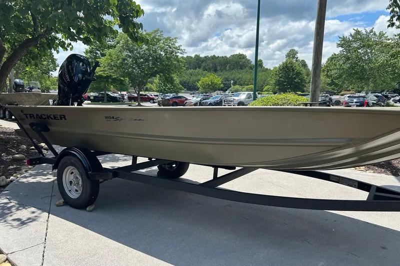 Slide: The Image of 2026 Tracker Grizzly 1654 T Sportsman boat on trailer, parked outdoors under trees. - 3