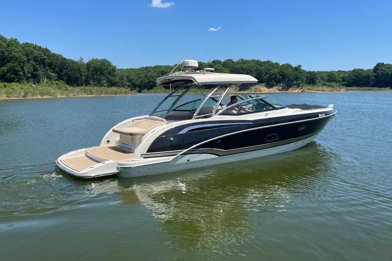 Slide: The Image of 2014 Formula 350 Crossover Bowrider I/O cruising on a serene lake under a clear blue sky. - 4