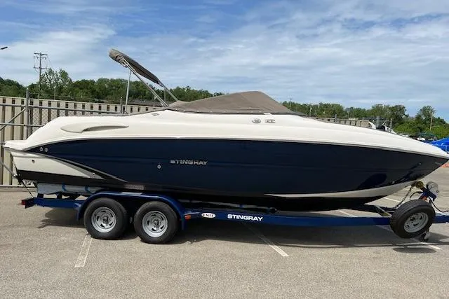 The Image of 2014 Stingray 250 LR boat on trailer, parked outdoors under a clear sky. - 0