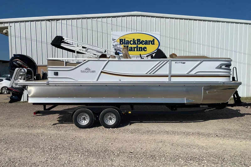 The Image of 2026 SunCatcher Elite 324 SS pontoon boat on trailer at BlackBeard Marine dealership. - 1