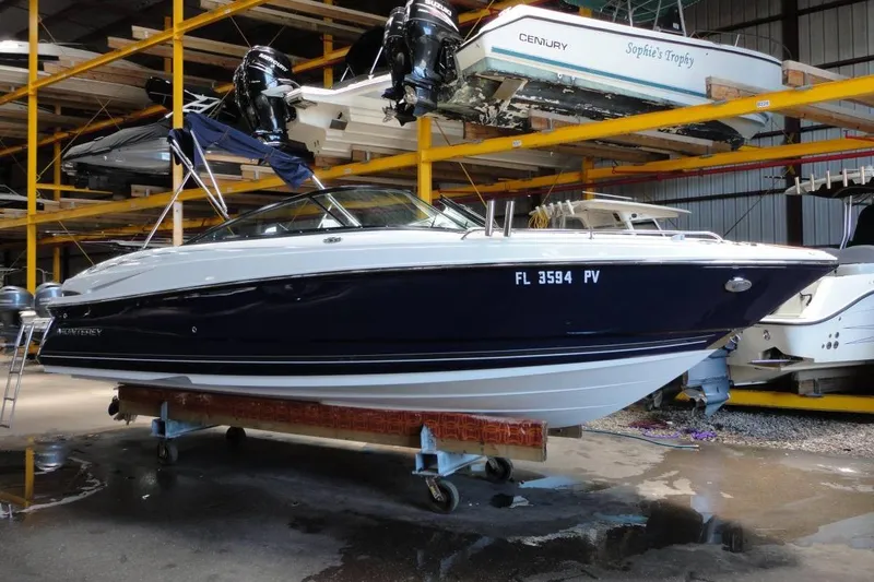 Slide: The Image of 2015 Monterey 264FS boat in storage, featuring sleek design and dark blue hull. - 1