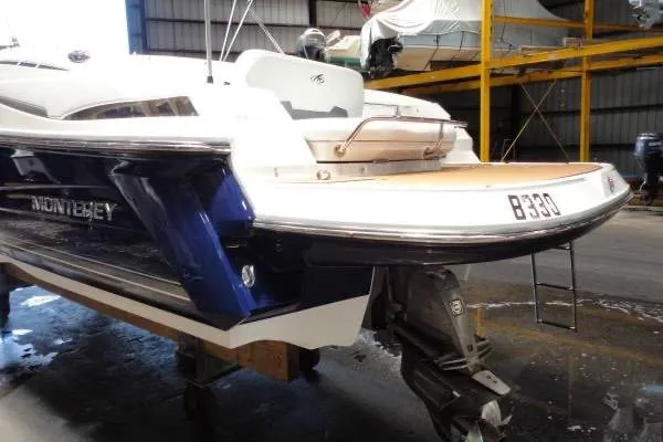 Slide: The Image of 2015 Monterey 264FS boat in a warehouse, showcasing stern and outboard motor. - 3