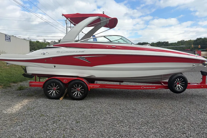 The Image of 2026 Crownline 278 SS boat in red and white on a trailer, parked outdoors. - 0
