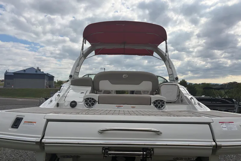 Slide: The Image of 2026 Crownline 278 SS boat with red canopy, rear view, parked outdoors under cloudy sky. - 15