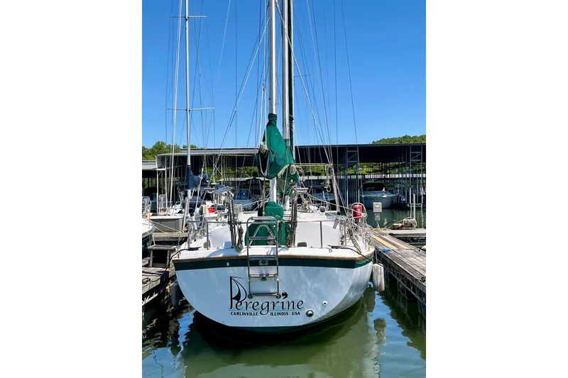 Slide: The Image of 1979 Pearson 424 sailboat docked, named "Peregrine," in a marina under clear blue skies. - 2