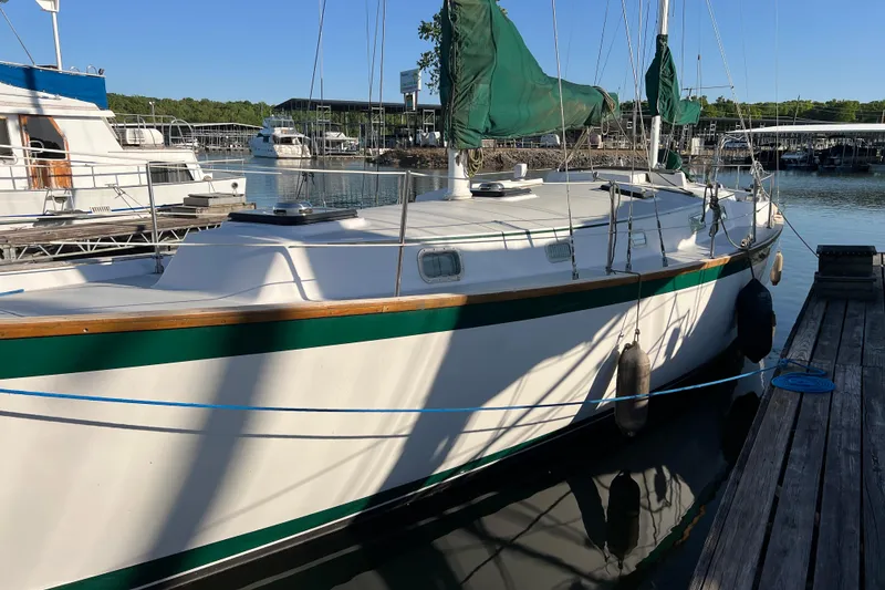 Slide: The Image of 1979 Pearson 424 sailboat docked at marina with green sail covers. - 23