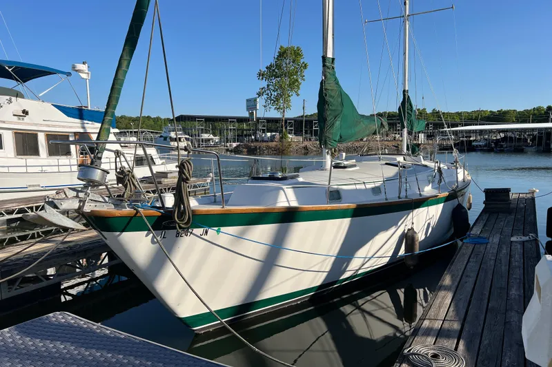 Slide: The Image of 1979 Pearson 424 sailboat docked at marina, featuring green sails and white hull. - 3