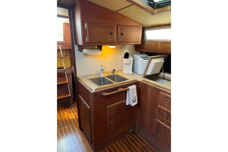 Slide: The Image of 1979 Pearson 424 yacht galley with wooden cabinets, dual sinks, and compact appliances. - 48