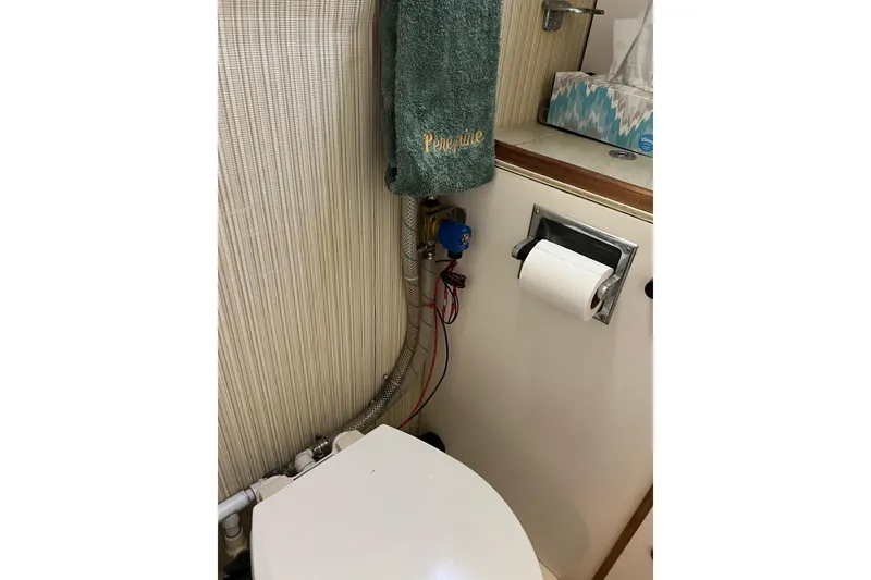 Slide: The Image of 1979 Pearson 424 yacht bathroom with toilet, towel, and tissue holder. - 57