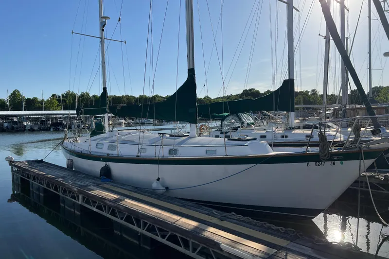 Slide: The Image of 1979 Pearson 424 sailboat docked at a marina, surrounded by calm water and other boats. - 7