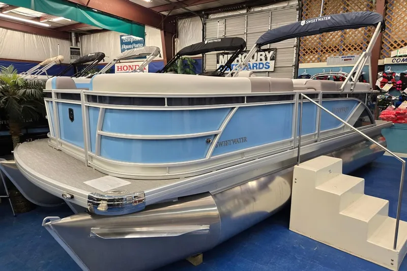 The Image of 2026 Godfrey Sweetwater 2086 C pontoon boat displayed indoors, featuring blue and white design. - 0