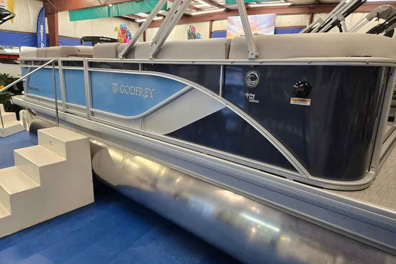 Slide: The Image of 2026 Godfrey Sweetwater 2086 C pontoon boat displayed indoors with blue and gray design. - 2