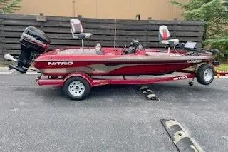 The Image of Red 2002 Nitro NX 882 SC fishing boat on trailer, parked outdoors. - 0