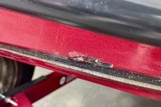 Slide: The Image of Close-up of a red 2002 Nitro NX 882 SC with visible paint damage. - 26