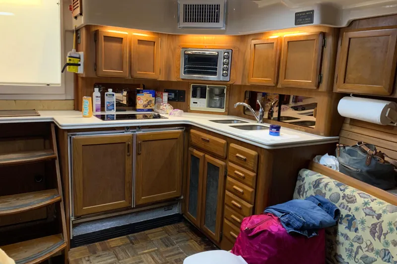 Slide: The Image of 1996 Luhrs 38 Open yacht kitchen with wooden cabinets, appliances, and cozy seating area. - 10