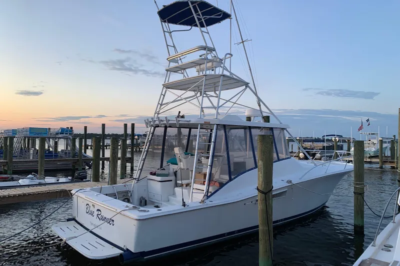 Slide: The Image of 1996 Luhrs 38 Open boat docked at sunset, featuring a tall tower and spacious deck. - 2