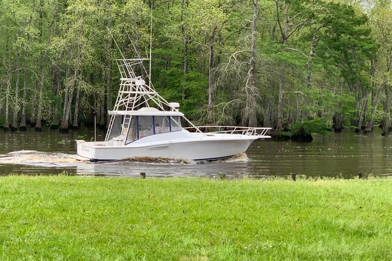 Slide: The Image of 1996 Luhrs 38 Open boat cruising on a serene river with lush green trees. - 6