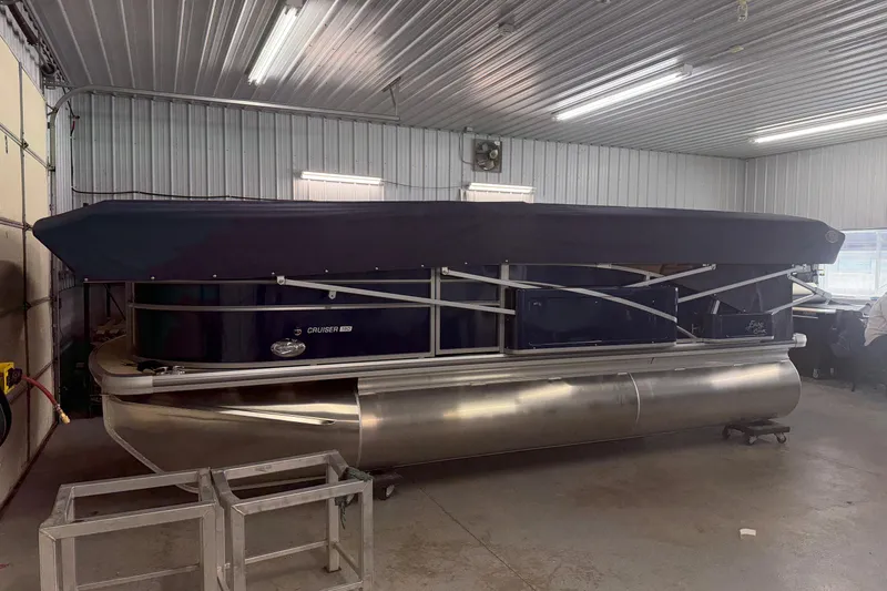 Slide: The Image of 2026 Harris Cruiser 190 SL pontoon boat in a garage with a protective cover. - 1