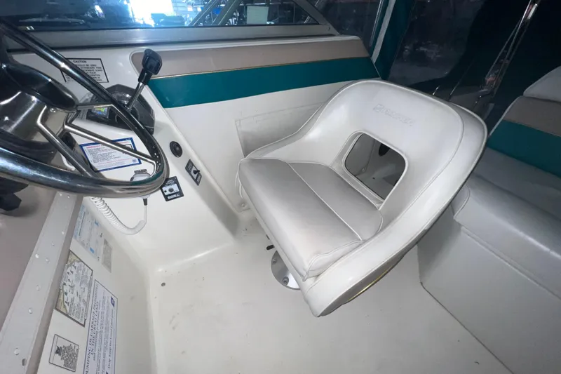 Slide: The Image of 1995 Rinker Fiesta Vee 265 boat interior with steering wheel and white captain's chair. - 14