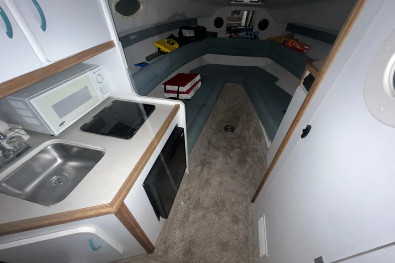 Slide: The Image of Interior of a 1995 Rinker Fiesta Vee 265 boat with kitchenette and seating area. - 15