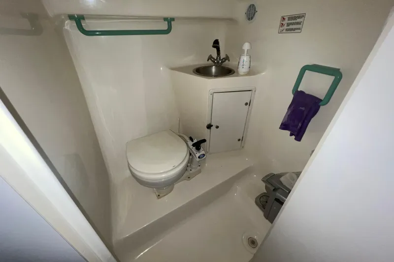 Slide: The Image of 1995 Rinker Fiesta Vee 265 boat bathroom with toilet, sink, and storage cabinet. - 20