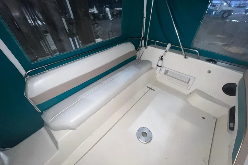Slide: The Image of 1995 Rinker Fiesta Vee 265 boat interior with white seating and teal canopy. - 3