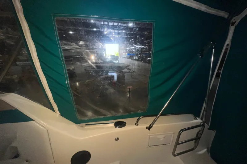 Slide: The Image of 1995 Rinker Fiesta Vee 265 boat interior with green canopy and window view. - 8