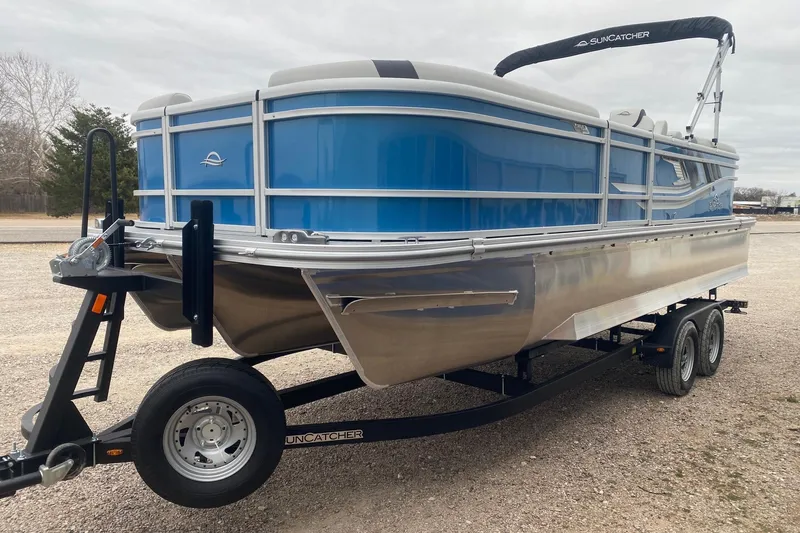 Slide: The Image of 2026 SunCatcher Select 322RC pontoon boat on trailer, featuring sleek blue design. - 4