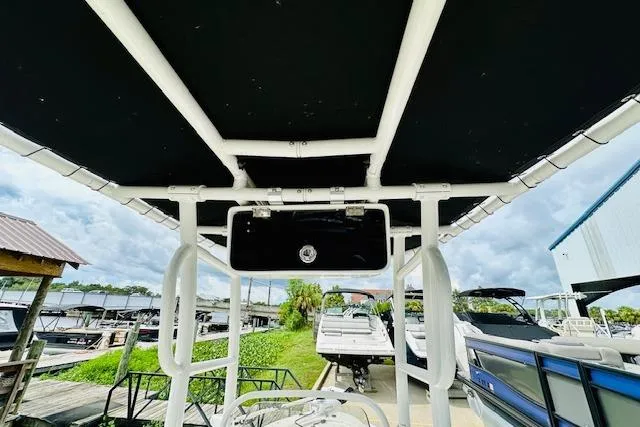 Slide: The Image of 2023 Mako 18 LTS boat with canopy, docked near other boats under a cloudy sky. - 15
