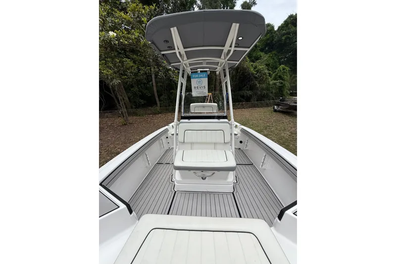 Slide: The Image of 2020 Yamaha Boats 195 FSH Sport interior with seating and canopy, set in a wooded area. - 14