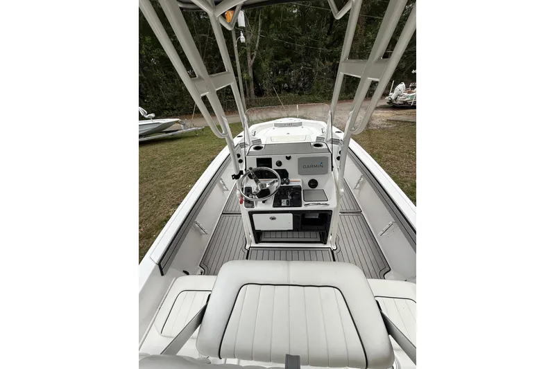 Slide: The Image of 2020 Yamaha Boats 195 FSH Sport interior with steering console and seating, parked on grass. - 5