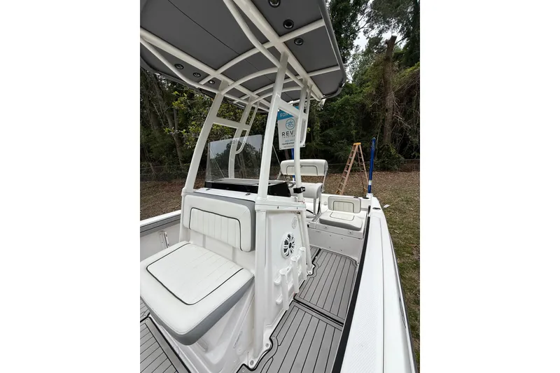 Slide: The Image of 2020 Yamaha Boats 195 FSH Sport interior with seating and canopy, surrounded by trees. - 6