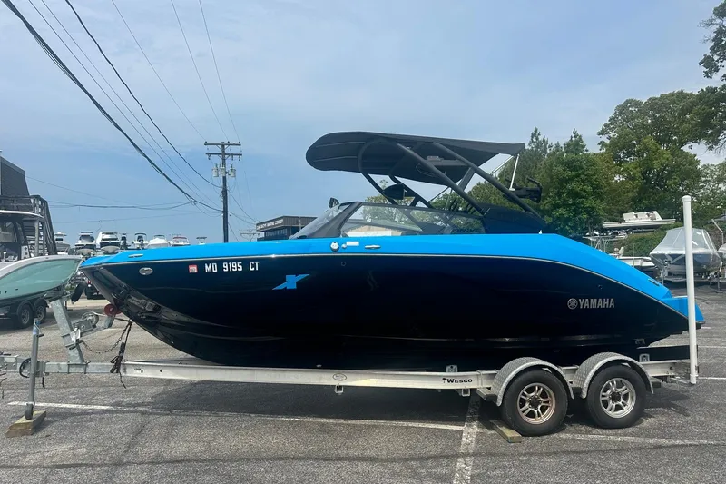 The Image of 2023 Yamaha Boats 222XD in blue and black on a trailer, parked outdoors. - 0