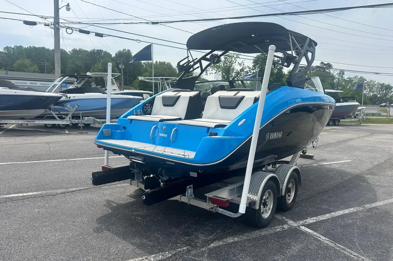 Slide: The Image of 2023 Yamaha Boats 222XD in blue, parked on a trailer in a dealership lot. - 3
