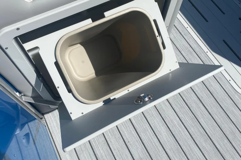 Slide: The Image of Open storage compartment on 2026 SunCatcher Select 322RC boat, featuring a built-in trash bin. - 14
