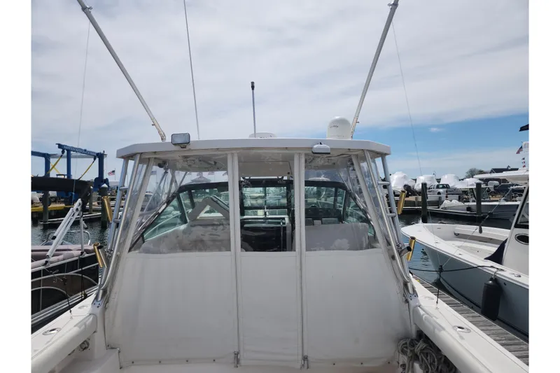 Slide: The Image of 2003 Tiara Yachts 3100 Open LE at marina, showcasing cockpit and fishing rods. - 15