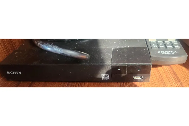 Slide: The Image of A Sony electronic device with USB port and Insignia remote on a wooden surface. - 34